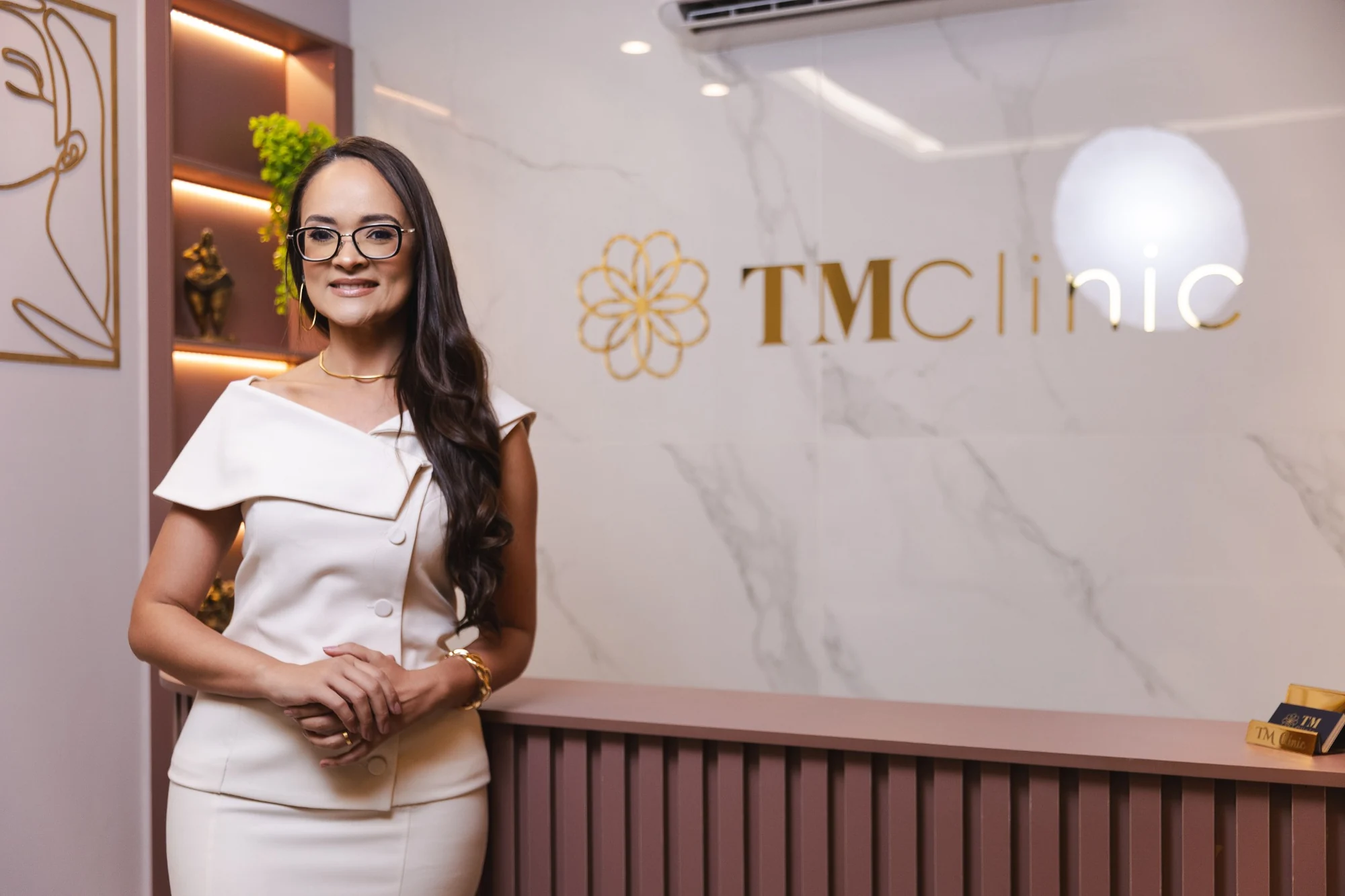 Dra. Thais Menezes na recepção da TM Clinic, ao lado da marca